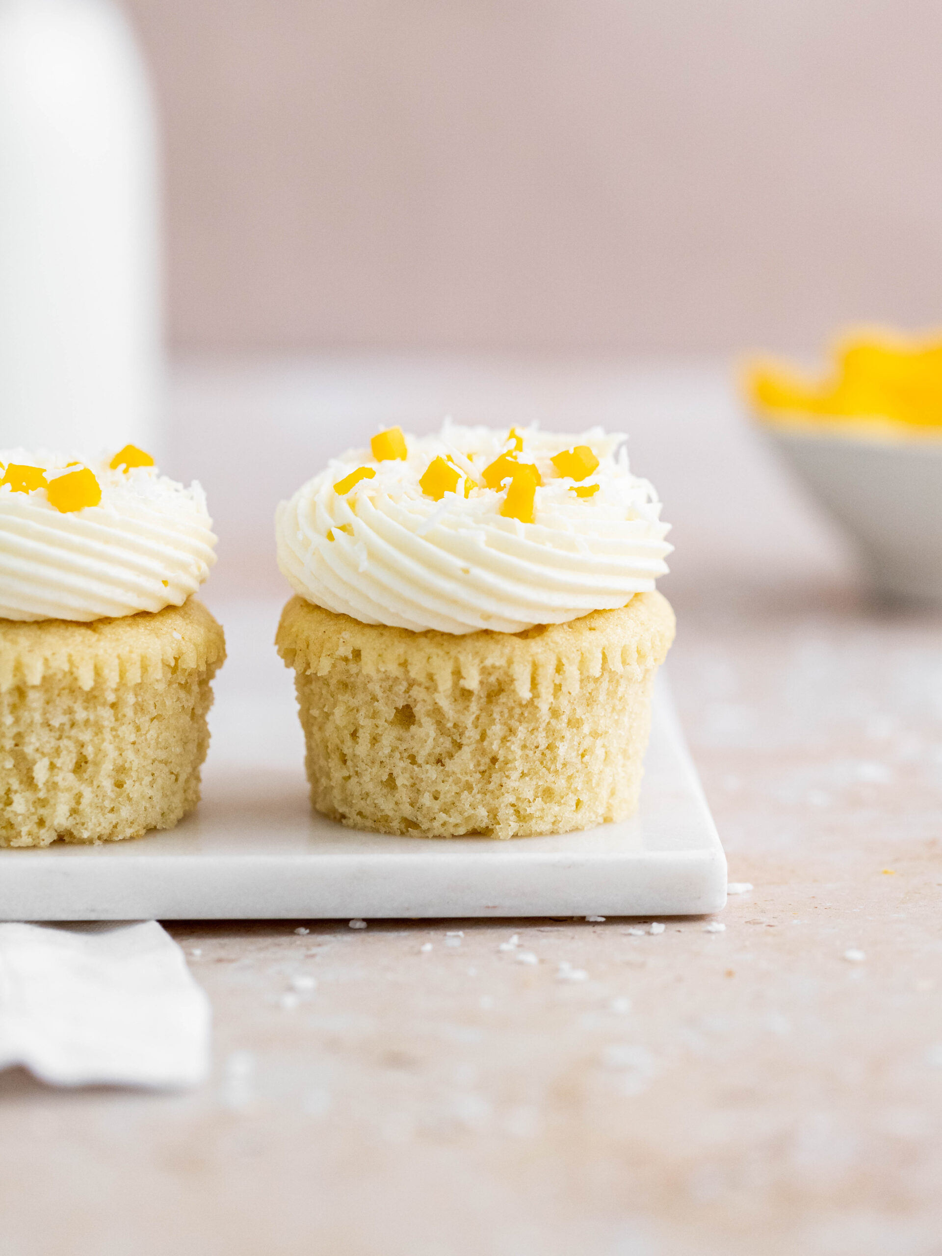 Coconut and mango cupcakes on a tray.