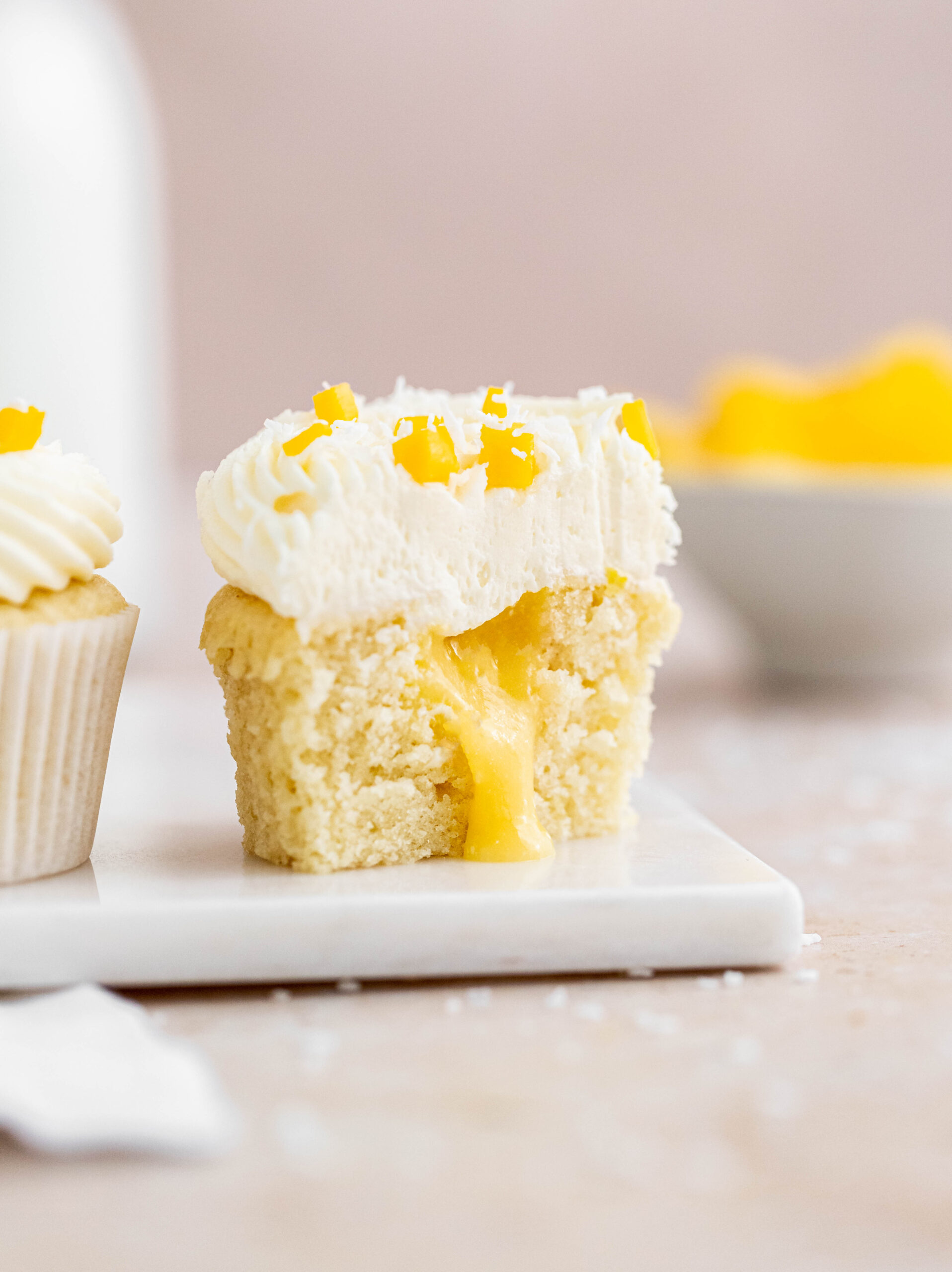Coconut cupcake cut in half with mango curd spilling out.