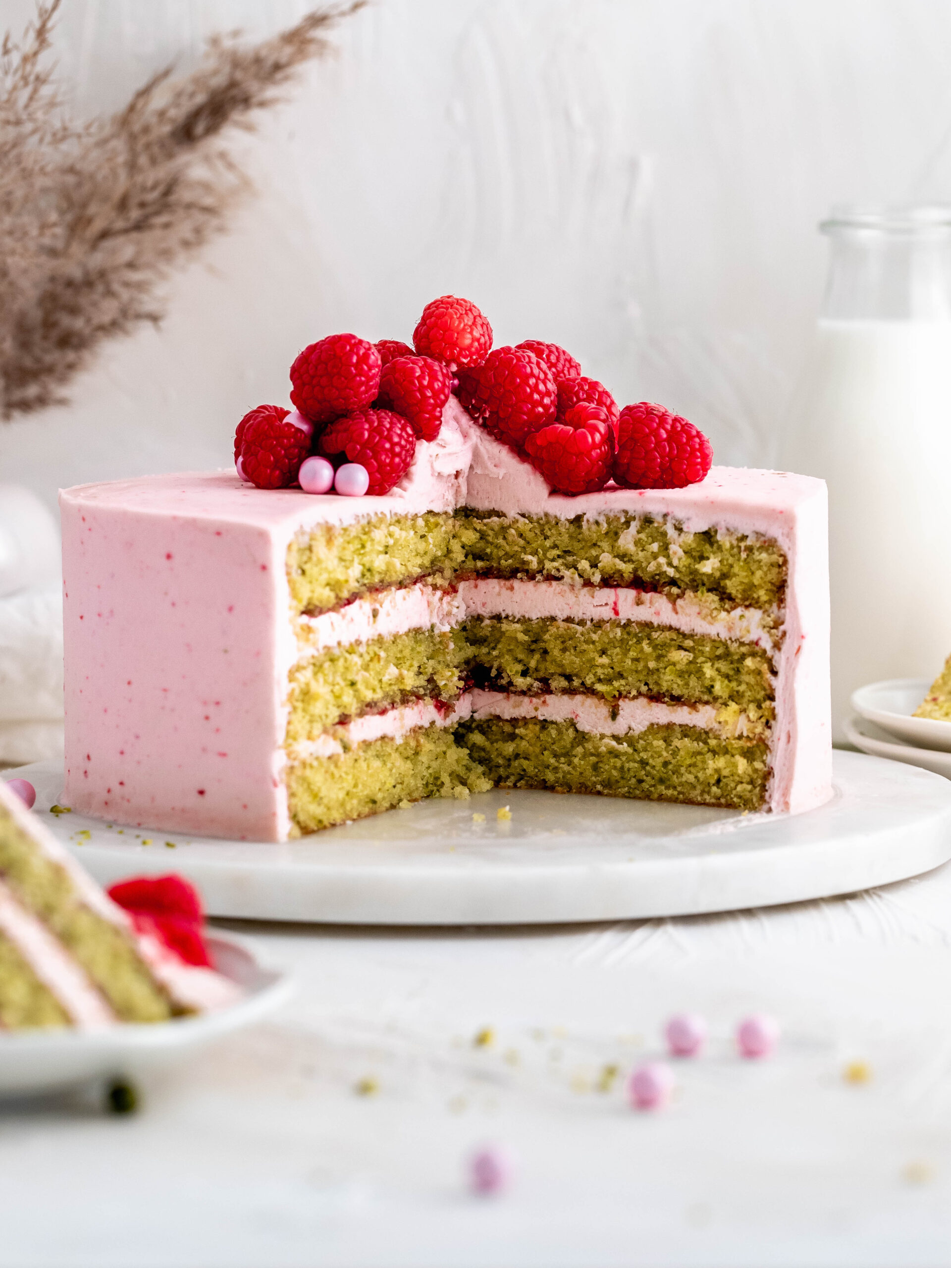 Raspberry pistachio layer cake on a cake stand. 
