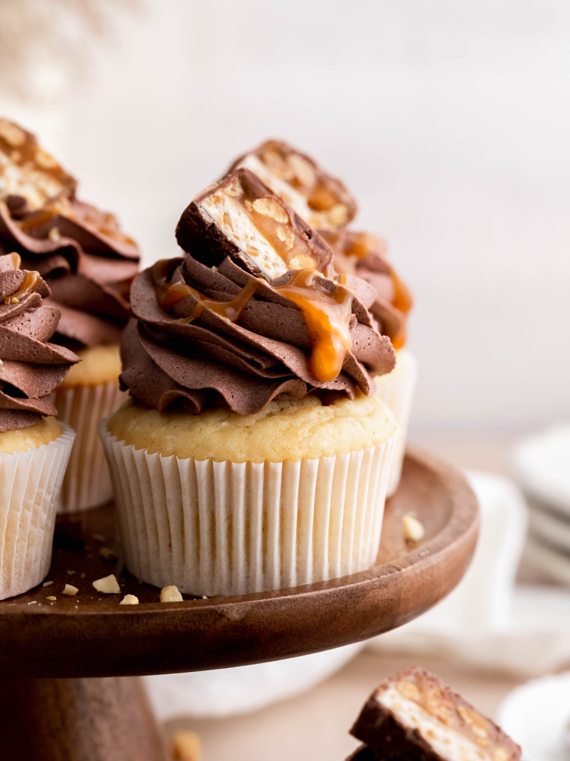 Snickers cupcakes on cake stand.