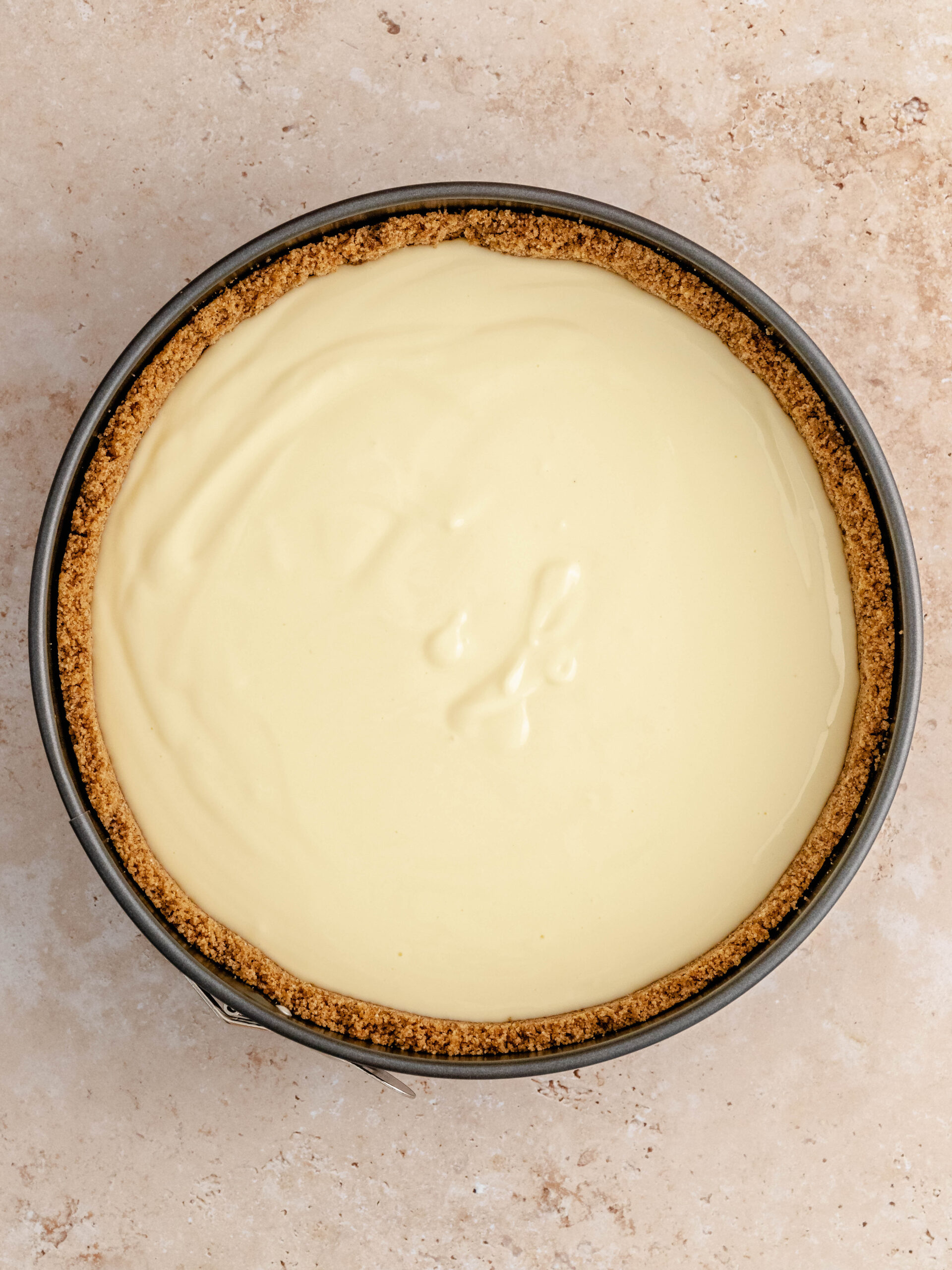 Fyldet med cheesecake hældes i kagebunden.
