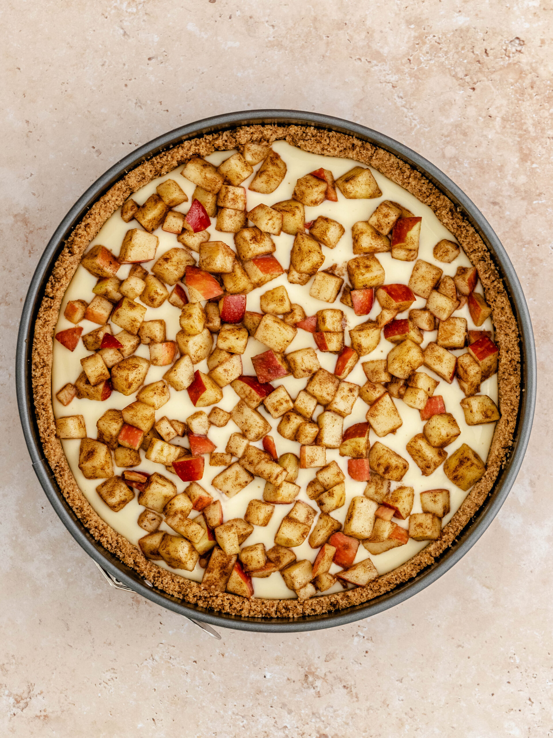 The prepared apples placed on top of the cheesecake.