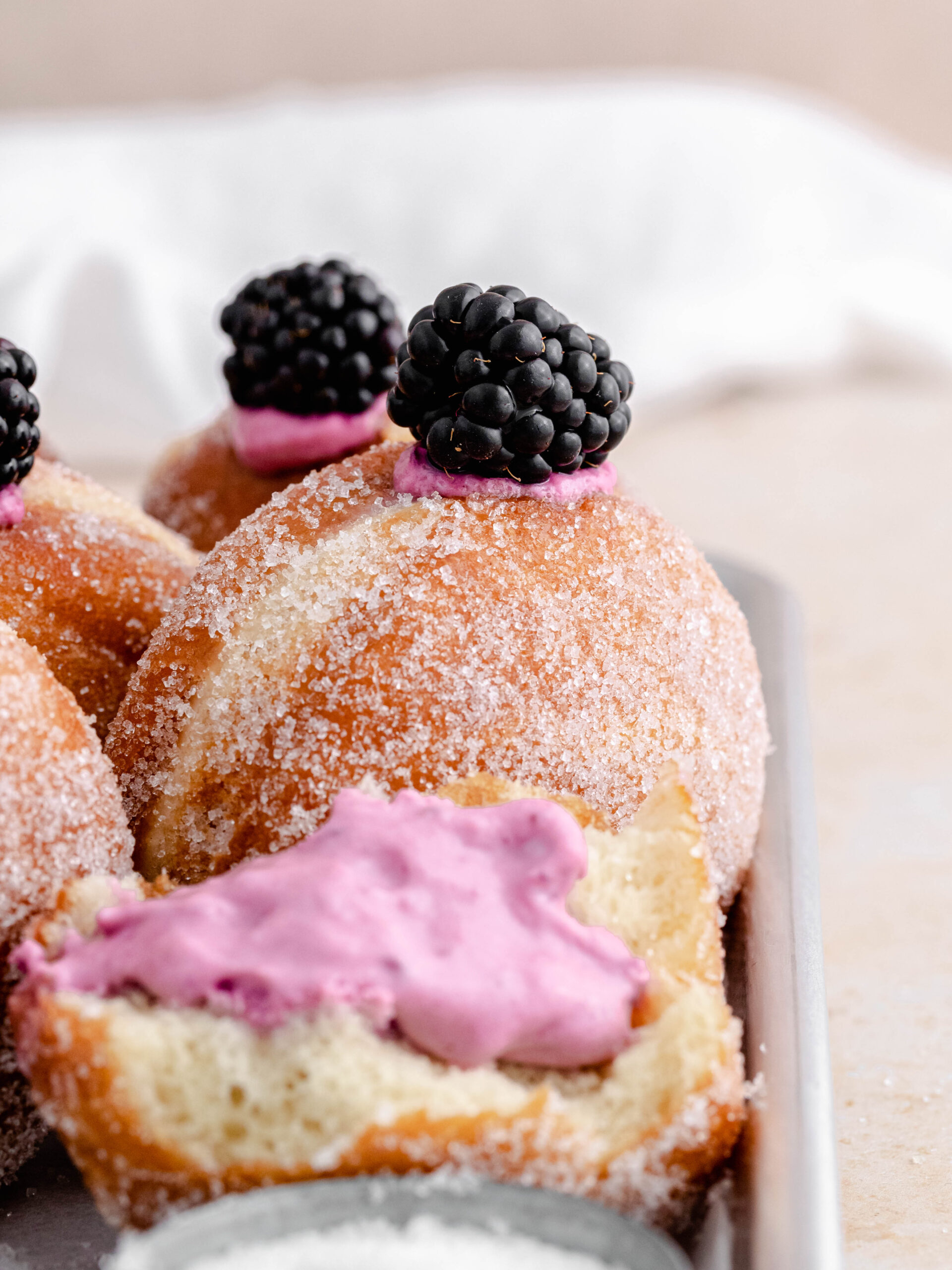 Filled blackberry cheesecake donuts on a tray.