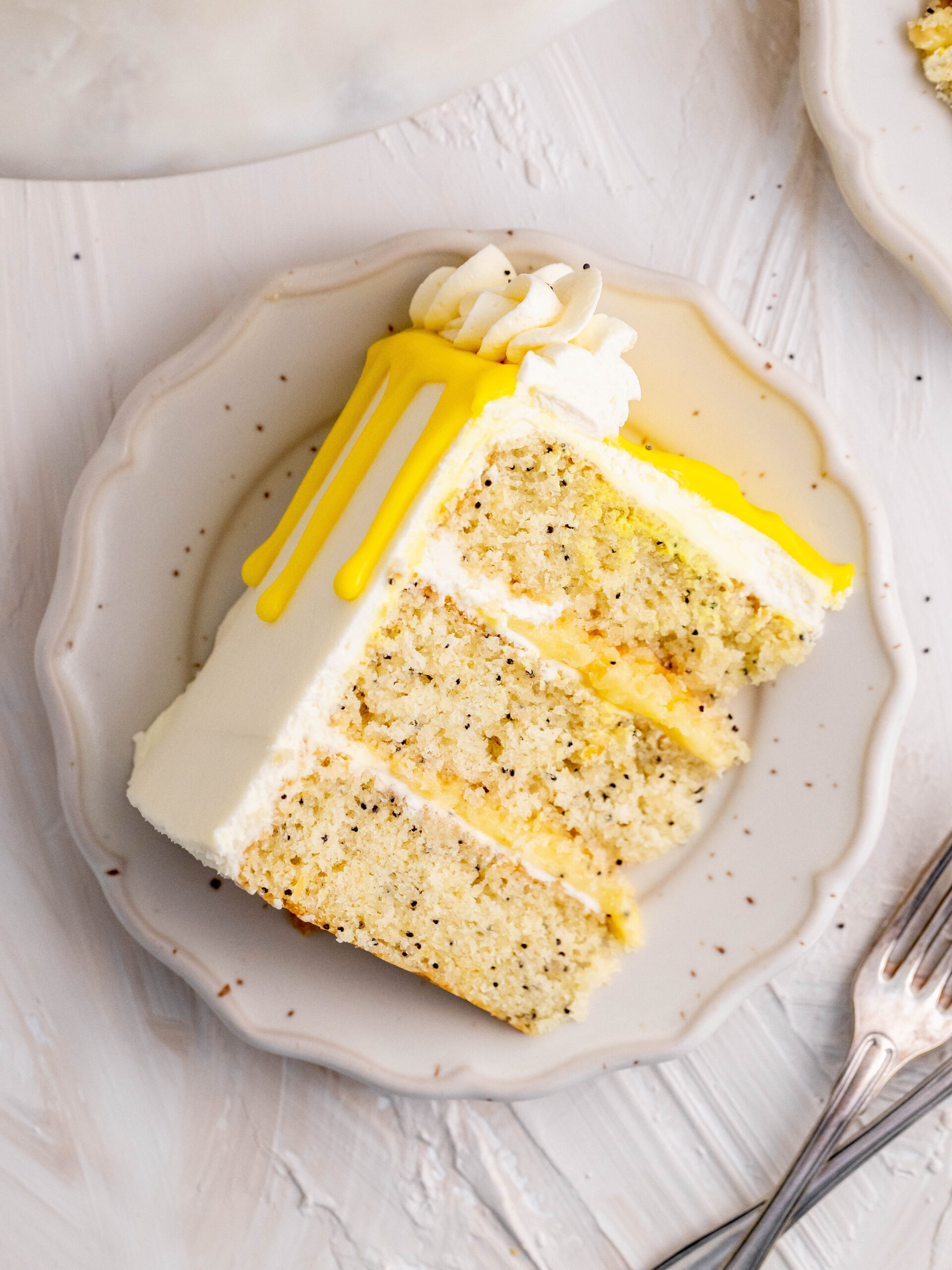 A slice of lemon poppy seed layer cake on a plate.