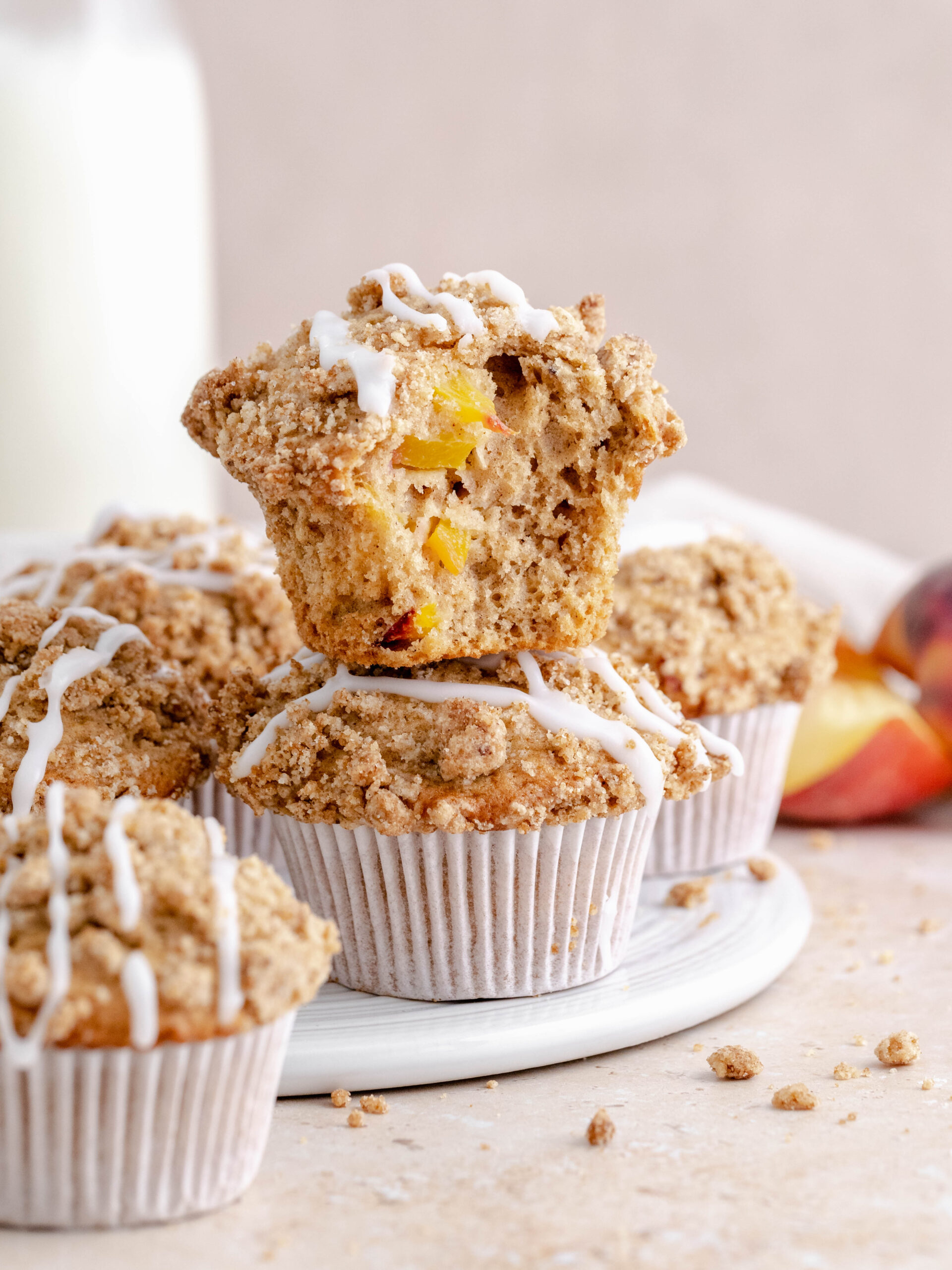 Peach crumble muffins stacked on a plate.