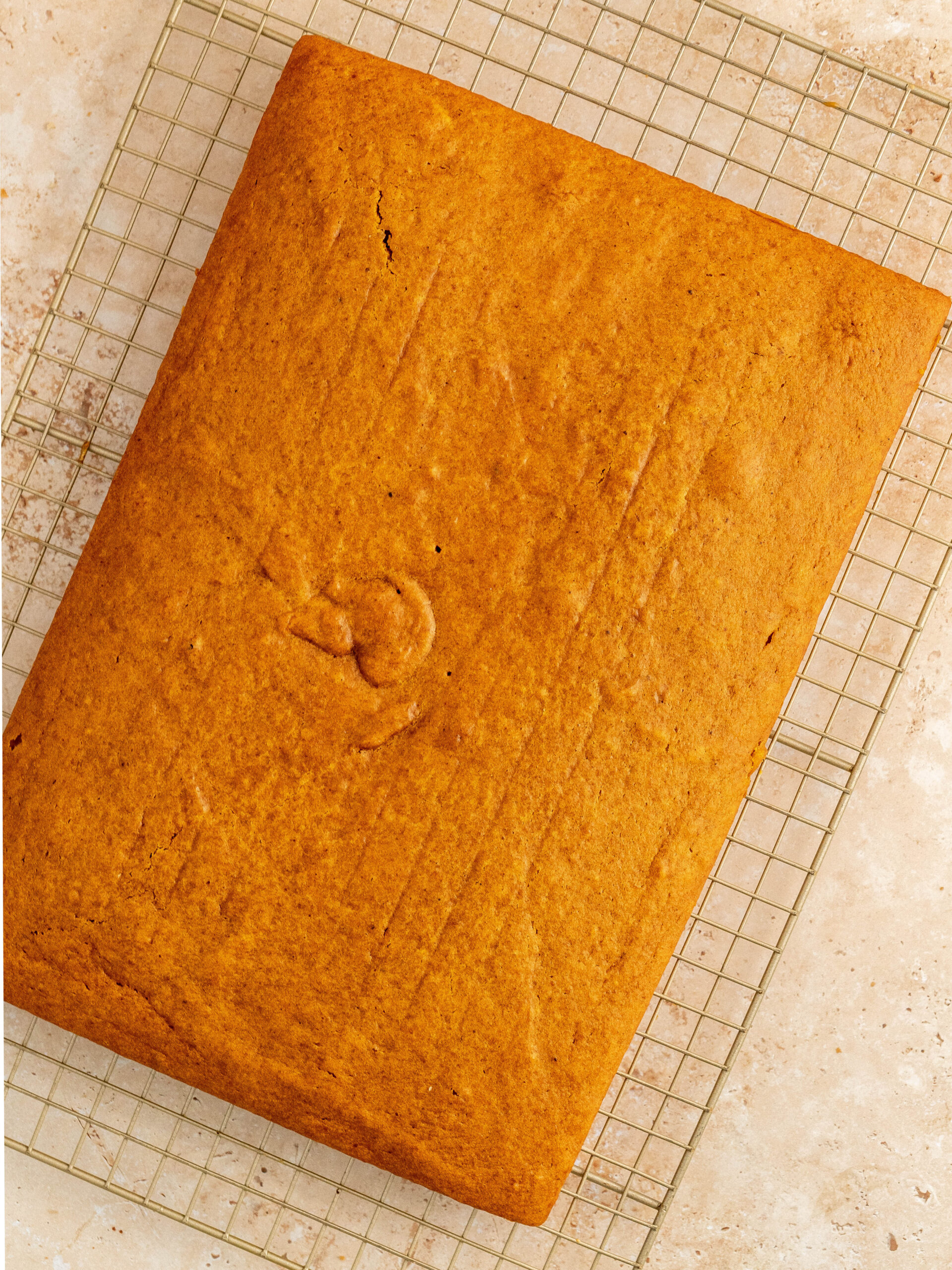 Finished baked pumpkin sheet cake on a cooling rack. 