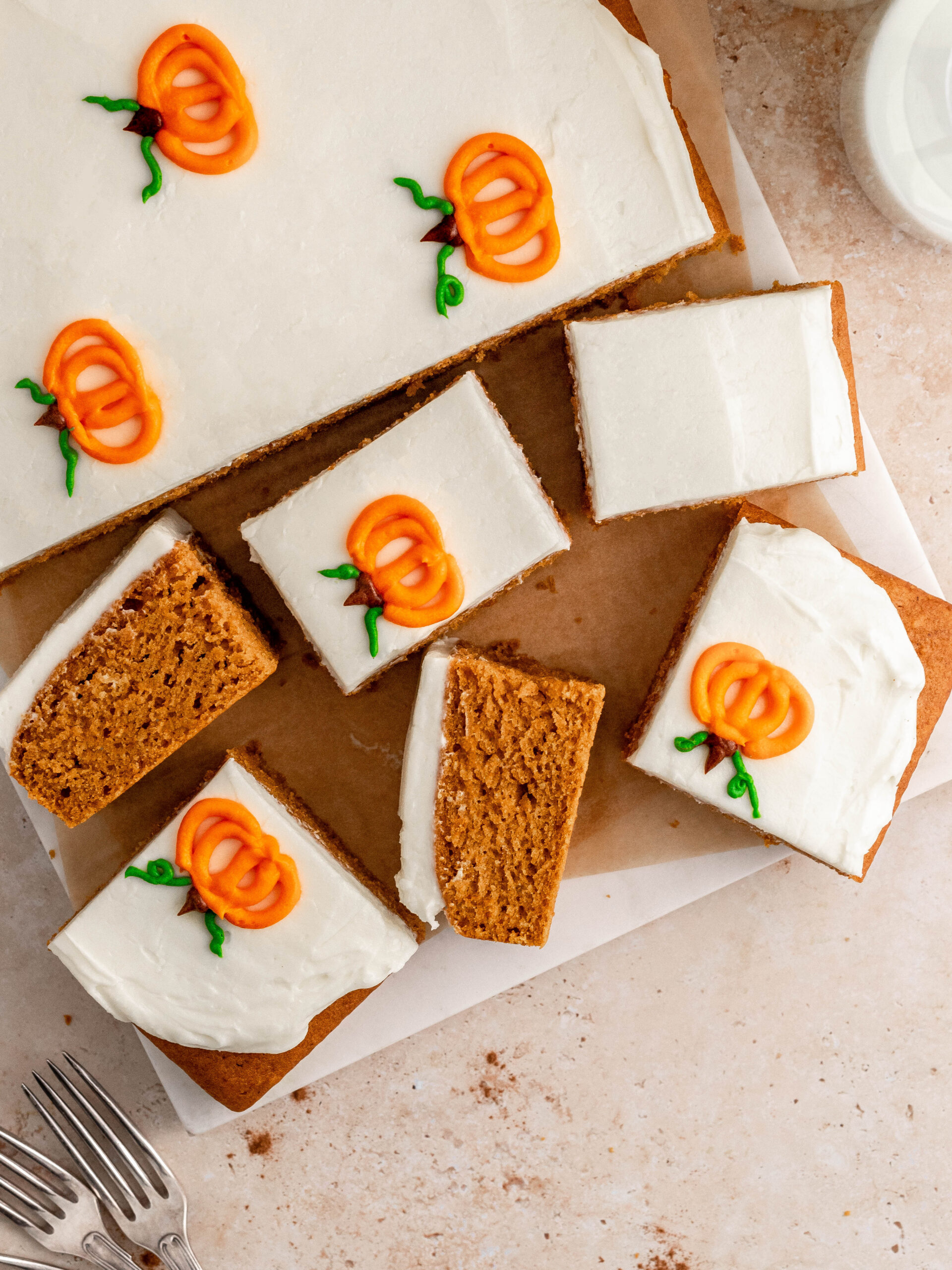 Pumpkin sheet cake on a cake tray, cut into slices.