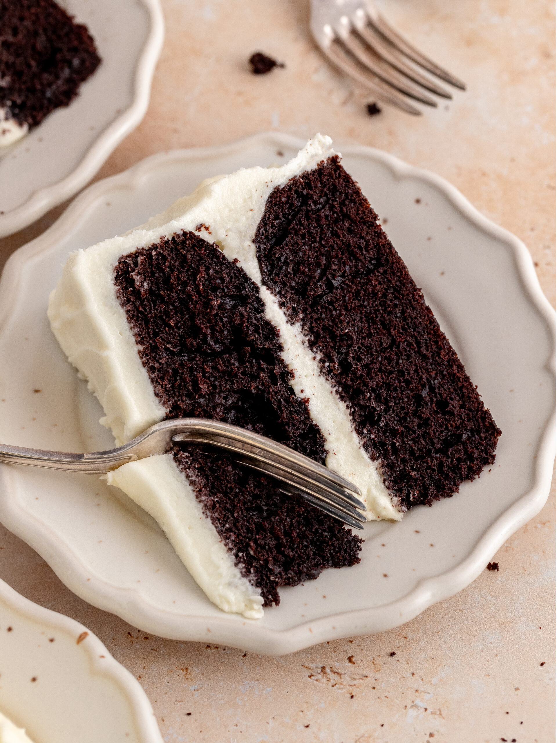A slice of chocolate cake with cream cheese frosting on a plate.