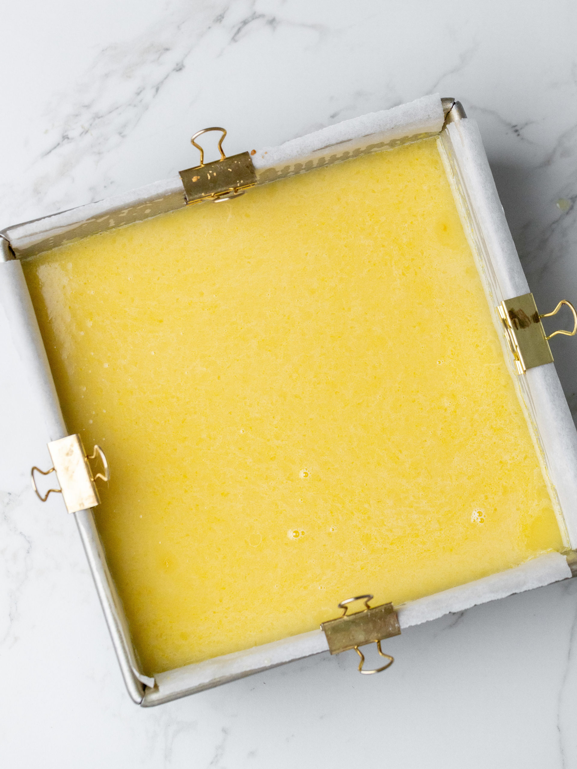 Hæld citronfyldet over mørdejbunden inden bagning.