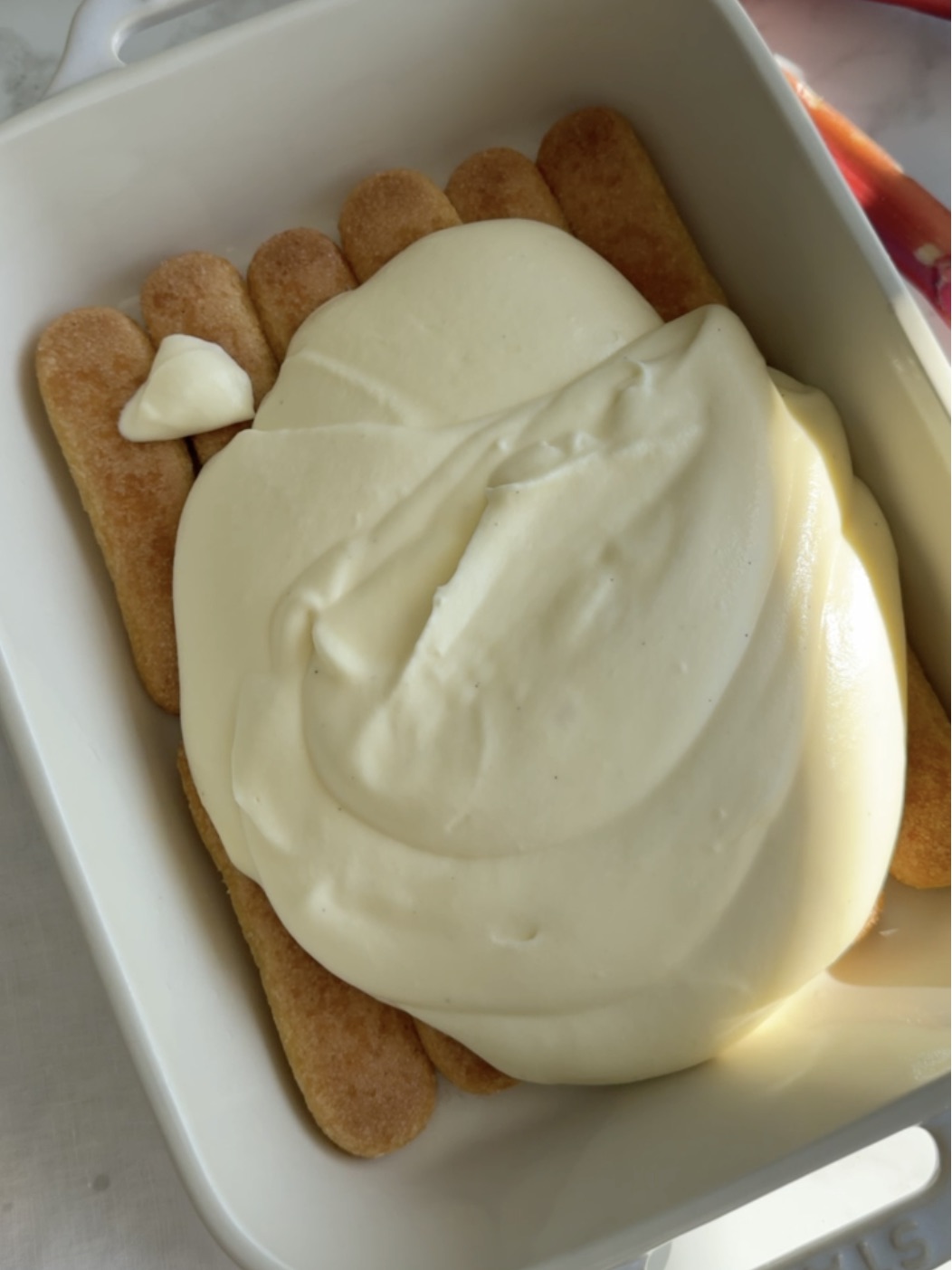 a layer of ladyfingers and mascarpone filling in a serving dish.
