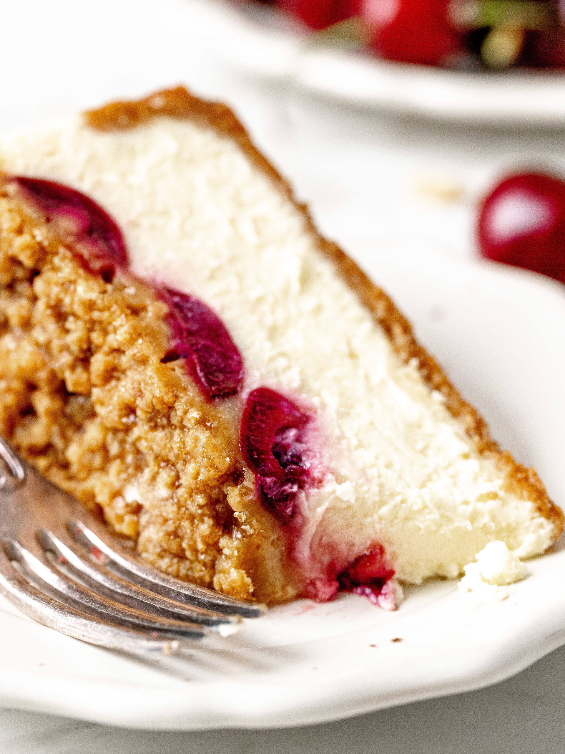 Slice of cherry crumble cheesecake on a plate