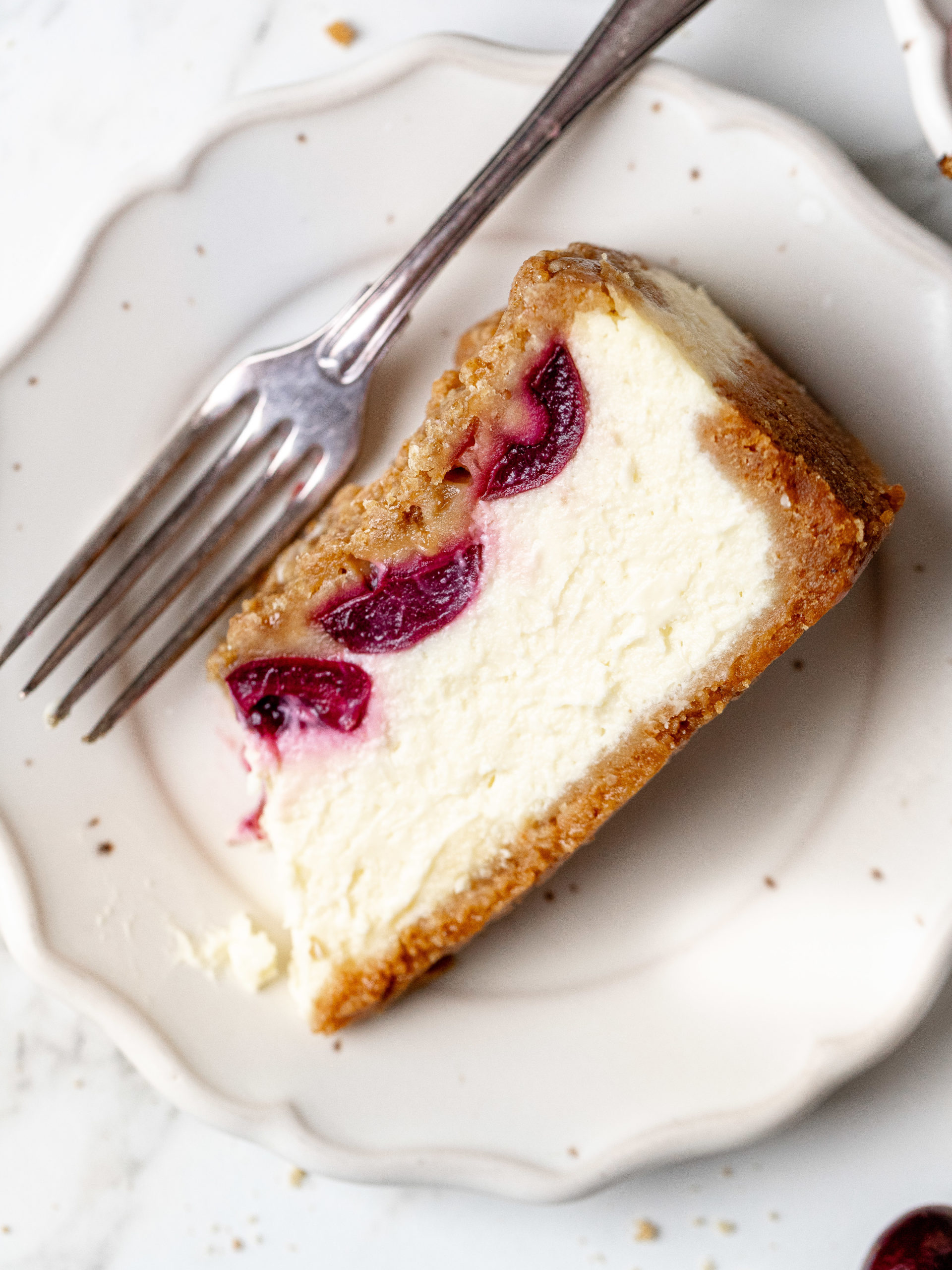 Slice of cherry crumble cheesecake on a plate