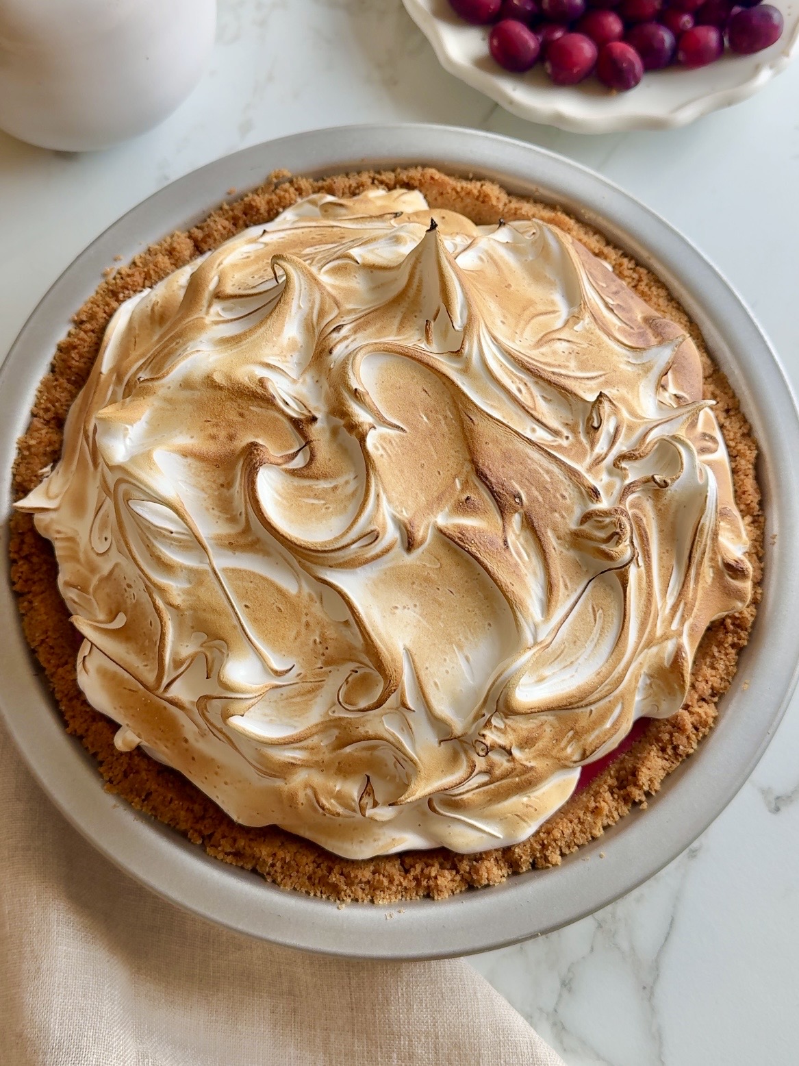 Tærte med tranebær og marengs med en cremet fyldning af tranebærcreme og ristet marengs.